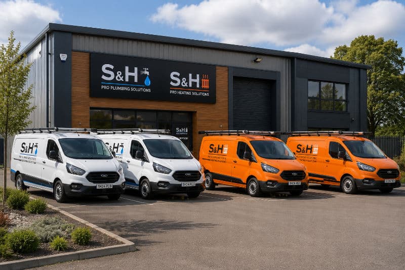 S&H plumbing and heating service vans parked outside the company building.